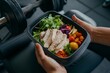© NASSRI - Man holding a plastic black container box healthy fitness meal including white meat diet, fresh green salad and vegetables dish Tasty calorie lunch protein foods, athlete muscle building, gym interior