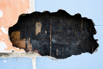 Wall Mural - A hole in a wall with a black and brown surface