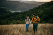 © La Famiglia - Couple holding hands and trekking together with an amazing view in the background