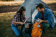 © La Famiglia - Young couple sitting at the top of the mountain over a fire