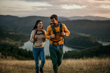 shot of a couple going for a hike up the mountain, lake in the background