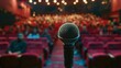 © Salman - A microphone is on a stage in front of a crowd of people. The microphone is the focus of the image, and the audience is watching the performance. Scene is one of anticipation and excitement.