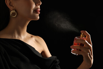 Canvas Print - Woman spraying perfume on black background, closeup