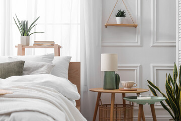 Poster - Stylish living room interior with bed, bedside tables, lamp and houseplants