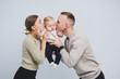 © DSMT - A family with a baby in their arms at home. Happy young family mom dad and newborn baby smiling and kissing on room background, loving family at home
