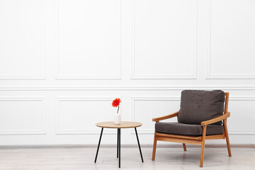 Sticker - Comfortable armchair and coffee table with gerbera flower near white wall, space for text. Interior design