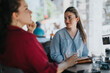 © qunica.com - Two young business associates having a casual outdoor meeting at a cafe, engaging in conversation on a sunny day.