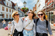 © Kyryl Gorlov - Three cheerful young adult women friend with kids walk street old european german town city street enjoy having fun laughing sunny day together. Female persons friendship celebration party weekend