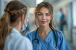 © DachAI - A young female nurse, dressed in blue scrubs and a stethoscope, smiles warmly while engaging with a colleague, showcasing warmth, healthcare teamwork, and professionalism.
