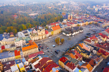 Wall Mural - View from drone on large central square of Czech city of Jihlava overlooking medieval cathedrals, red steeple of Town Hall and modern shopping mall in fall morning..