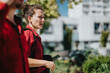 © qunica.com - Business professionals walking in the city, engaged in a discussion while enjoying a sunny day. Office buildings and greenery in the background.