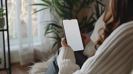 Poster - Mockup image of a woman holding and using mobile phone with blank desktop white screen at home : Generative AI