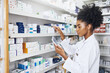 © JordaanExams/peopleimages.com - African woman, check or tablet with screen in pharmacy for stock inspection, report for medicine inventory. Female pharmacist, drug store or ebook for digital record of health information or research