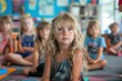 © Kedsaraporn - A young girl with blonde hair and blue eyes sits in a classroom, listening attentively to her teacher.