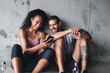 © A. Frank/peopleimages.com - Man, woman and exercise break with mobile app for fitness podcast, streaming in building for wellness. Couple, phone or workout together with rest in parking lot for health, music for gym or training