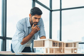 Smart civil architect engineer looking while planing design house construction with blueprint, house model and architectural equipment. Designer measuring and inspecting house model. Design. Tracery.