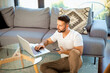 © sepy - Casual man sitting at home and using laptop and smartphone