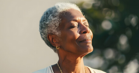 Wall Mural - Close up portrait of mature black woman with short gray hair standing in sunlight, peaceful and contemplative expression