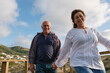 © Westend61 - Smiling couple holding hands and having fun under cloudy sky
