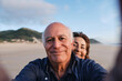 © Westend61 - Smiling senior man taking selfie with woman at beach
