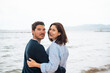 © Westend61 - Smiling man and woman standing together in front of sea at beach
