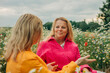© Westend61 - Smiling woman talking to sister sitting in chamomile field