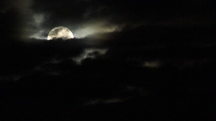 Wall Mural - The full moon shines down on the Earth at night, with occasional clouds obscuring the light.