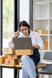 © David - Portrait business woman smile and use laptop checking information on parcel shipping box before send to customer. Entrepreneur small business working at home. SME business online marketing.