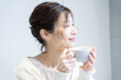 © amanaimages - コーヒーカップを持ってのんびりしている女性