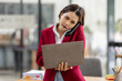 © David - Portrait of young asian financial woman sitting at desk and working on laptop while making call phone