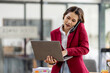 © David - Portrait of young asian financial woman sitting at desk and working on laptop while making call phone