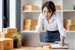 © David - SME concept. Young asian female ecommerce business owner prepares package box for customer and delivery check balance.  SME small business entrepreneur SME or freelance