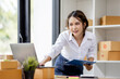 © David - Startup small business entrepreneur SME, asian woman checks stock on clipboard and parcels at home ,Success small business owner online sell marketing delivery, SME e-commerce telemarketing concept