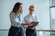 © Jacob Lund - Woman and her administrative assistant use a digital tablet together in an office