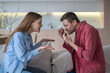© DimaBerlin - Shouting romantic couple sits face to face on couch, actively gesticulating and arguing using sign language at home, expressing emotions and perspectives through their animated hand movements.