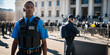 © ipolstock - African-American Secret Service agent standing guard outside government building. Crowd control barriers and other officers visible. Security, law enforcement, or government-related content.