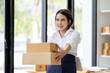 © David - Startup small business entrepreneur or freelance Asian woman using a laptop with box, Young success Asian woman with her hand lift up, online marketing packaging box and delivery, SME concept.