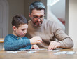 © peopleimages.com - Family, man and kid with puzzle by table at home for development, support and growth in logic. Thinking, father and son with memory game in living room for cognitive, learning and problem solving