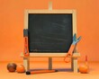 © Yasi Lens - Suitable for back-to-learning concepts, orange school tools on a wooden easel blackboard.