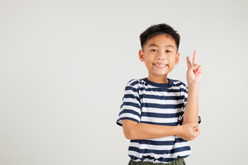 Asian young kid boy showcases optimism and peace by gesturing victory and peace signs in a studio shot with a white background. primary child joyful smile speaks of success, V sign finger