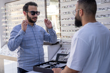 Wall Mural - Male selecting the best eyeglasses, also selecting sunglasses whihc is clips eyeglasses