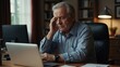 © muqadas - A senior man sitting at home office with computer and having headache