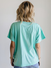 Wall Mural - A thin, athletic American woman in a loose neon aquamarine T-shirt. The model has short, wavy blonde hair that doesn't reach her shoulders. The photo was taken from behind