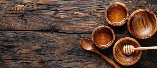 Poster - Wooden kitchen utensils like bowls spoons and a honey stick arranged on a wooden table background with three bowls a honey stick and two spoons A flat lay of wooden kitchenware showcasing a copy space