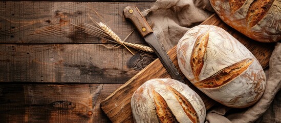 Poster - An overhead view of artisan bread on a rustic wooden backdrop with a vintage knife covered by a sackcloth featuring room for text or other elements in the image. with copy space image
