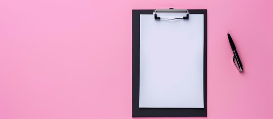 Wall Mural - Top view of a black clipboard on a pink surface with a blank sheet of paper featuring ample copy space image