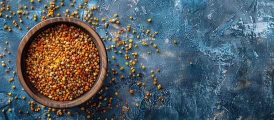 Aufkleber - Wooden bowl filled with bee pollen on a blue concrete background suitable for healthy nutrition with space for additional images