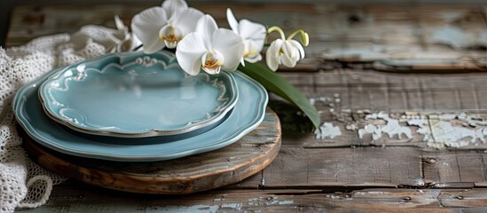 Wall Mural - Rustic retro kitchen table setting with old wooden board blue plate white orchid and lace towel under natural light and shade creating a nice vintage backdrop with copy space image