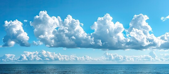 Fototapete - A scenic seascape with numerous white cumulus clouds against a blue sky creating a picturesque view with ample copy space image