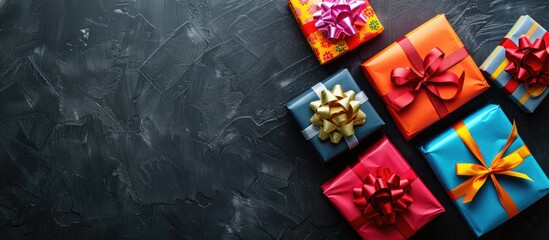 Poster - Gift boxes with colorful ribbons on black background seen from above providing copy space image
